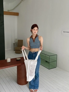 Detalle de un bolso shopper de malla de ganchillo blanco y un top de punto a rayas