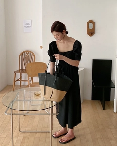 Dettaglio della borsa tote intrecciata bicolore con manici in pelle indossata da una modella