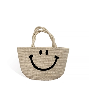 Handmade woven cotton straw beach bag for kids featuring a minimalist black smiley face