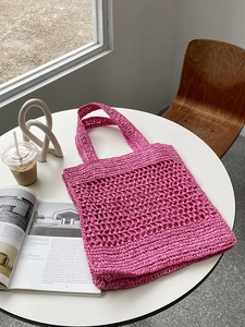 Primer plano del bolso tote rosa trenzado con textura de ganchillo en una mesa blanca