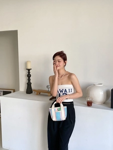 Détail du sac cabas tissé à rayures colorées avec un top blanc et un pantalon noir large