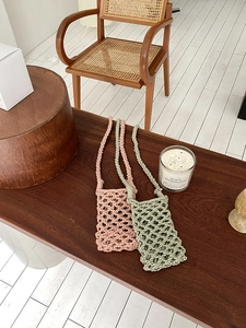Detail of hand-woven cotton rope phone bags in pink and green with hollow texture