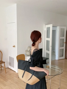 Dettaglio di grande borsa tote intrecciata bicolore con lunghi manici in pelle nera