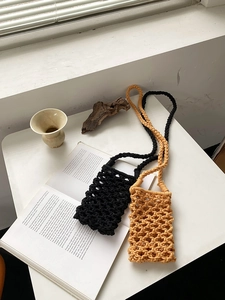 Detail view of handmade macrame phone bags in black and ginger on a minimalist desk