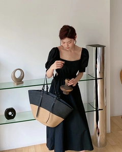 Dettaglio di una borsa tote bicolore in paglia con sottili manici in pelle nera