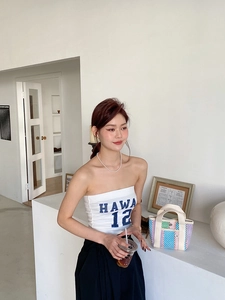 Détail d'un sac cabas tissé à rayures colorées avec un haut blanc et un pantalon noir