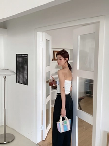 Tenue d'été minimaliste avec haut blanc, pantalon noir et sac cabas tressé à rayures