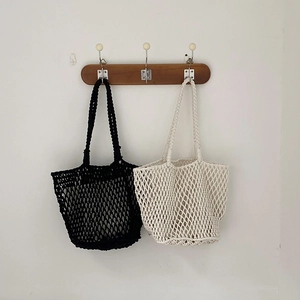 Close-up of handmade hollow woven shoulder bags in black and beige minimalist style