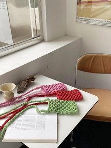 Detailed view of hand-woven cotton rope phone bags in pink, red and green colors
