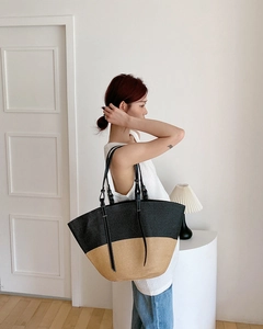 Dettaglio della grande borsa tote in paglia con manici in pelle nera e intreccio bicolore