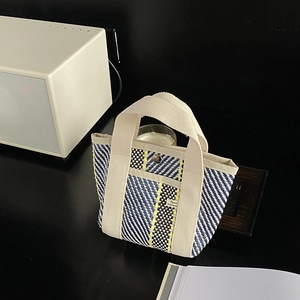 Détail du sac cabas en paille tissée avec rayures colorées et poignées en toile