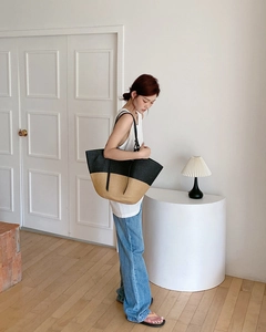 Dettaglio della grande borsa tote in paglia intrecciata con contrasto nero e pelle