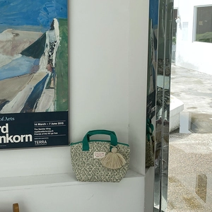 Détail du sac à déjeuner matelassé à fleurs avec anses vertes, pompons et étiquette