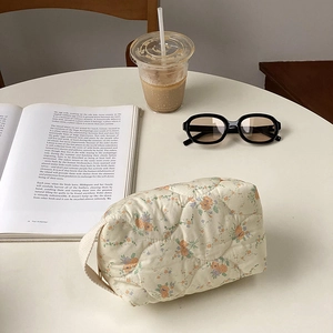 Detailed close-up of quilted floral cosmetic bag with cotton handle on a white table