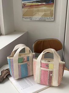 Détail de sacs cabas tissés à rayures colorées avec des poignées en toile sur un bureau