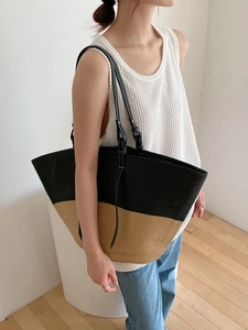 Borsa tote in paglia bicolore nero e marrone, indossata da una modella in stile casual