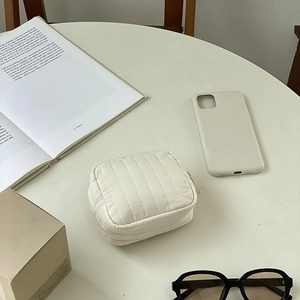 Minimalist beige quilted mini makeup bag and card holder on a stylish white table