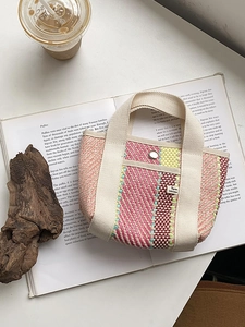Détail du sac cabas tissé avec rayures colorées, anses en toile et bouton pression