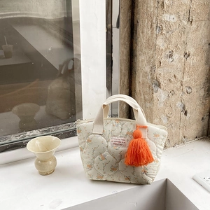 Gros plan du sac à lunch matelassé à fleurs avec gland orange et coutures ondulées