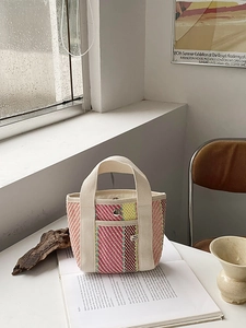 Détail macro d'un sac cabas tissé à rayures avec anses en toile et poche à boucle en métal