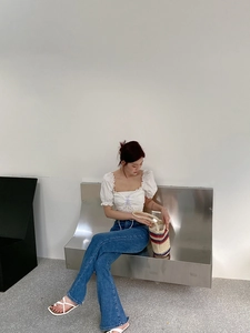 Close-up of a striped woven straw bucket bag paired with a white puff sleeve crop top