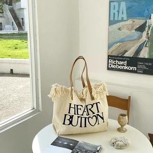 Detail of canvas tote with fringe edge, Heart Button print and brown leather handles