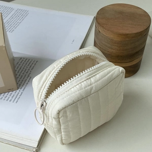 Close-up of beige quilted makeup bag featuring a smooth zipper and metal ring pull