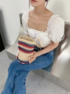 Close-up of handwoven straw bucket bag featuring nautical red and blue stripes
