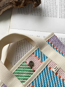 Détail d'un sac cabas tissé coloré avec motifs géométriques et boucle en métal argenté