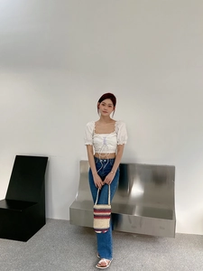Fashionable model posing with hand-woven straw bucket bag and white puff sleeve crop top