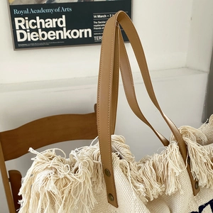 Detail of bohemian canvas tote with thick tassels and brown leather shoulder straps