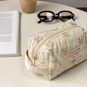 Beige quilted floral makeup bag with blue and orange flower patterns and woven handles