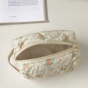 Quilted floral makeup bag with top zipper and side handle on a clean white background