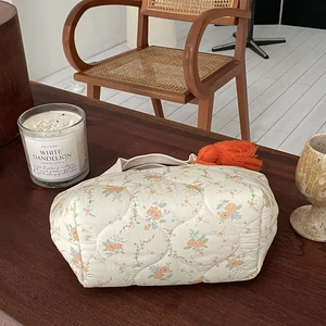 Gros plan d'un sac matelassé à fleurs avec gland orange sur une table en bois