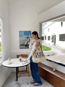Detail of the oversized canvas tote with fringe edges and brown leather shoulder straps