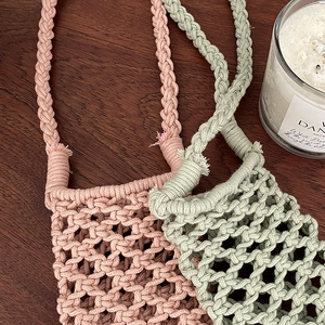 Handmade macrame cotton rope phone bags in pink and green with tassel details on wood