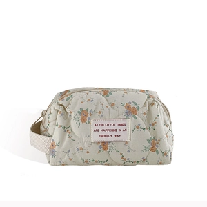 Quilted floral makeup bag in cream fabric with a convenient side handle and zipper closure