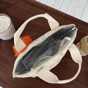 Sac déjeuner matelassé à fleurs avec gland orange montrant la doublure et le filet