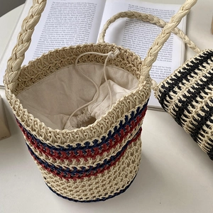 Detail of cylindrical straw bucket bag with red and blue stripes and drawstring lining