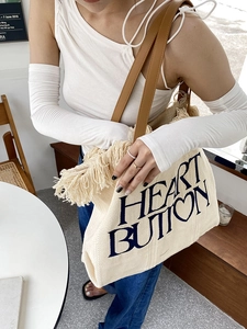 Detail of canvas tote bag with Heart Button print, boho fringes and brown leather strap