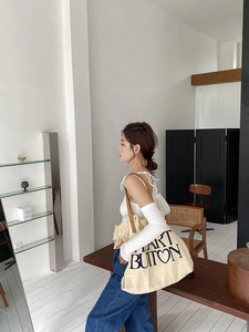 Detailed side view of a cream canvas tote bag with black art text and leather straps