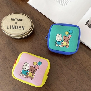 Detailed embroidery of cartoon animals on small canvas pouches over a wooden table