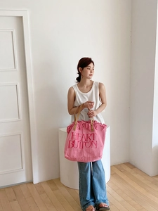 Pink canvas tote bag featuring Heart Button embroidery and leather handles in a macro detail