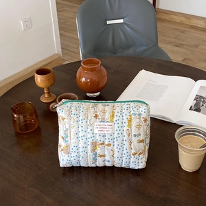Detailed view of cream quilted makeup bag with blue stars and cartoon character print