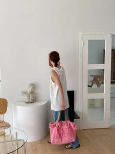 Pink canvas tote bag featuring fringe details and leather handles in a lifestyle setting