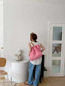 Pink canvas tote bag with Heart Button print and tassels shown on a model