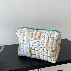 Close-up of quilted star and circus pattern makeup bag with a green zipper and label