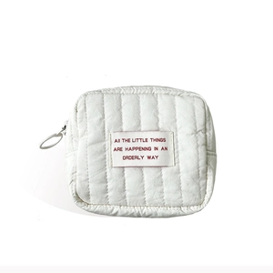 Mini white quilted makeup bag for women with decorative text and silver ring zipper