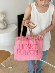 Detail of pink canvas tote featuring heart button embroidery and fringed edges