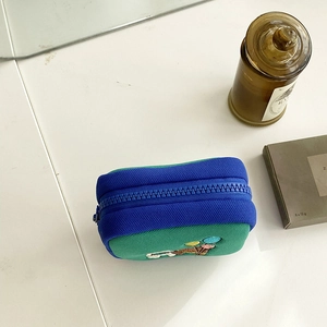 Close-up of small canvas storage pouch with zipper and colorful embroidery detail